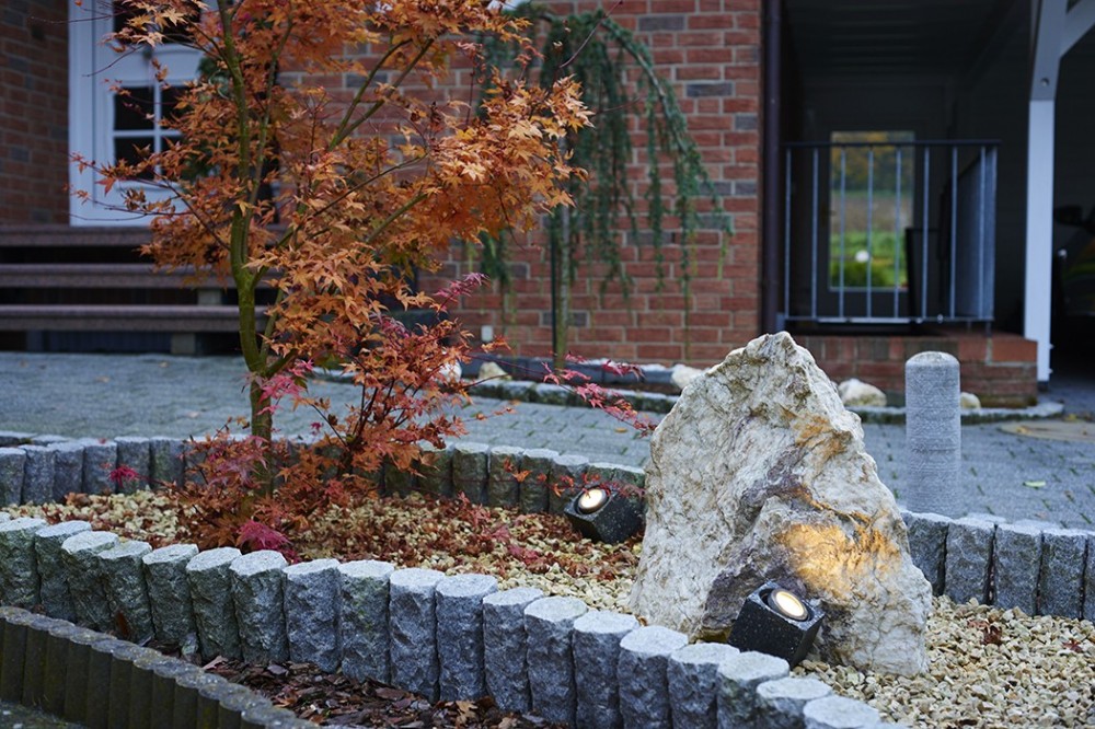 Gartengestaltung mit Naturstein und Beleuchtung in Vlotho Gestaltetes Gartenbeet mit Naturstein, Ziergehölz, Kies und integrierter Gartenbeleuchtung