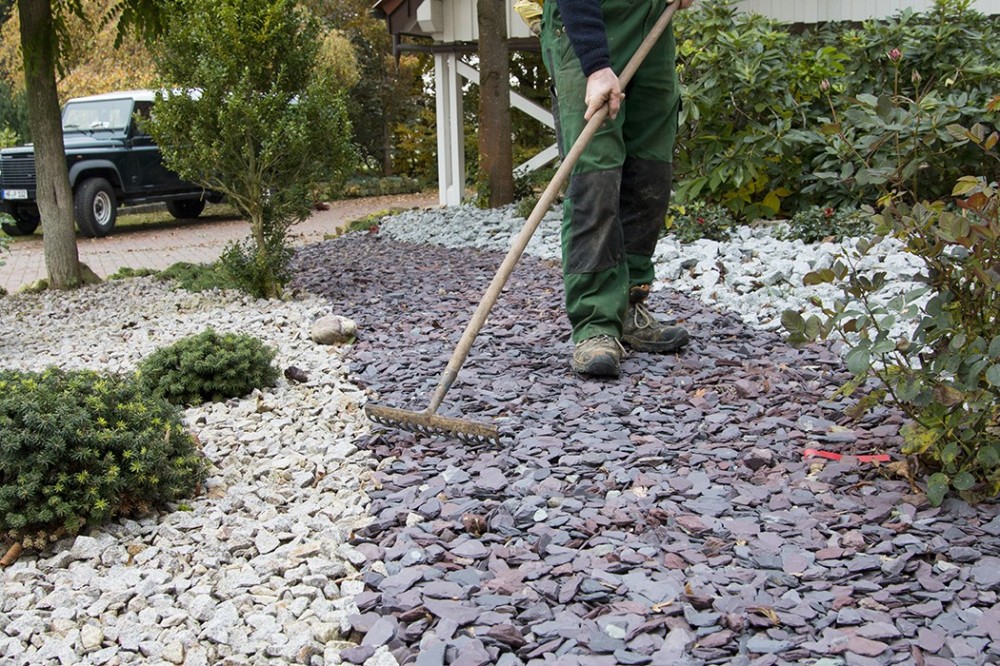 Gartenpflege von Ziersplittflächen in Vlotho Mitarbeiter bei der Pflege einer Ziersplittfläche mit Sträuchern und Gehölzen