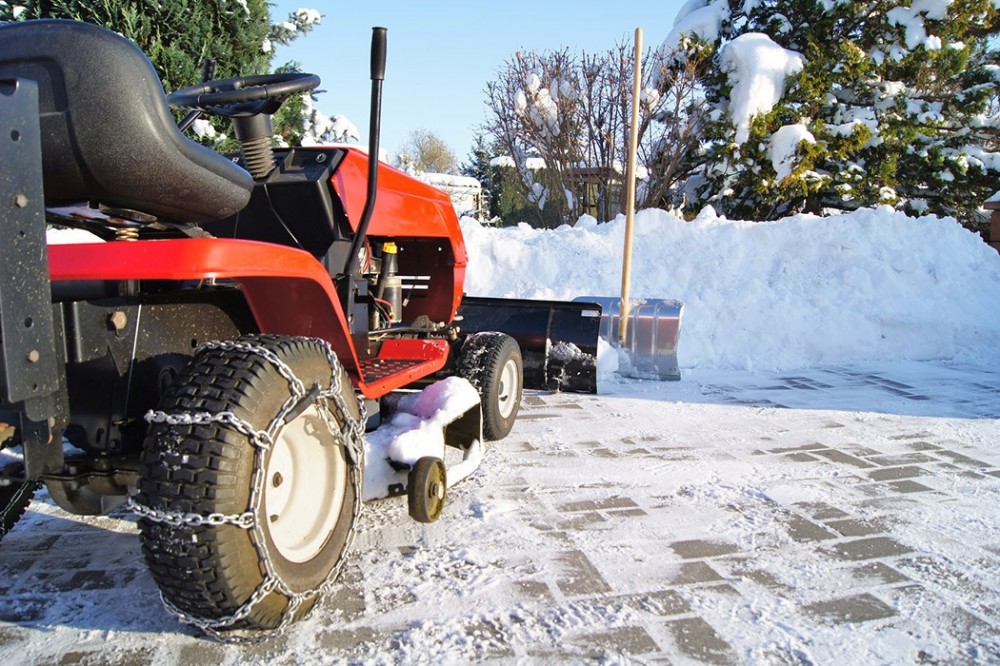 Winterdienst in Vlotho mit Schneepflug Kleines Räumfahrzeug mit Schneeschild und Schneeketten beim Winterdienst auf einer verschneiten Fläche